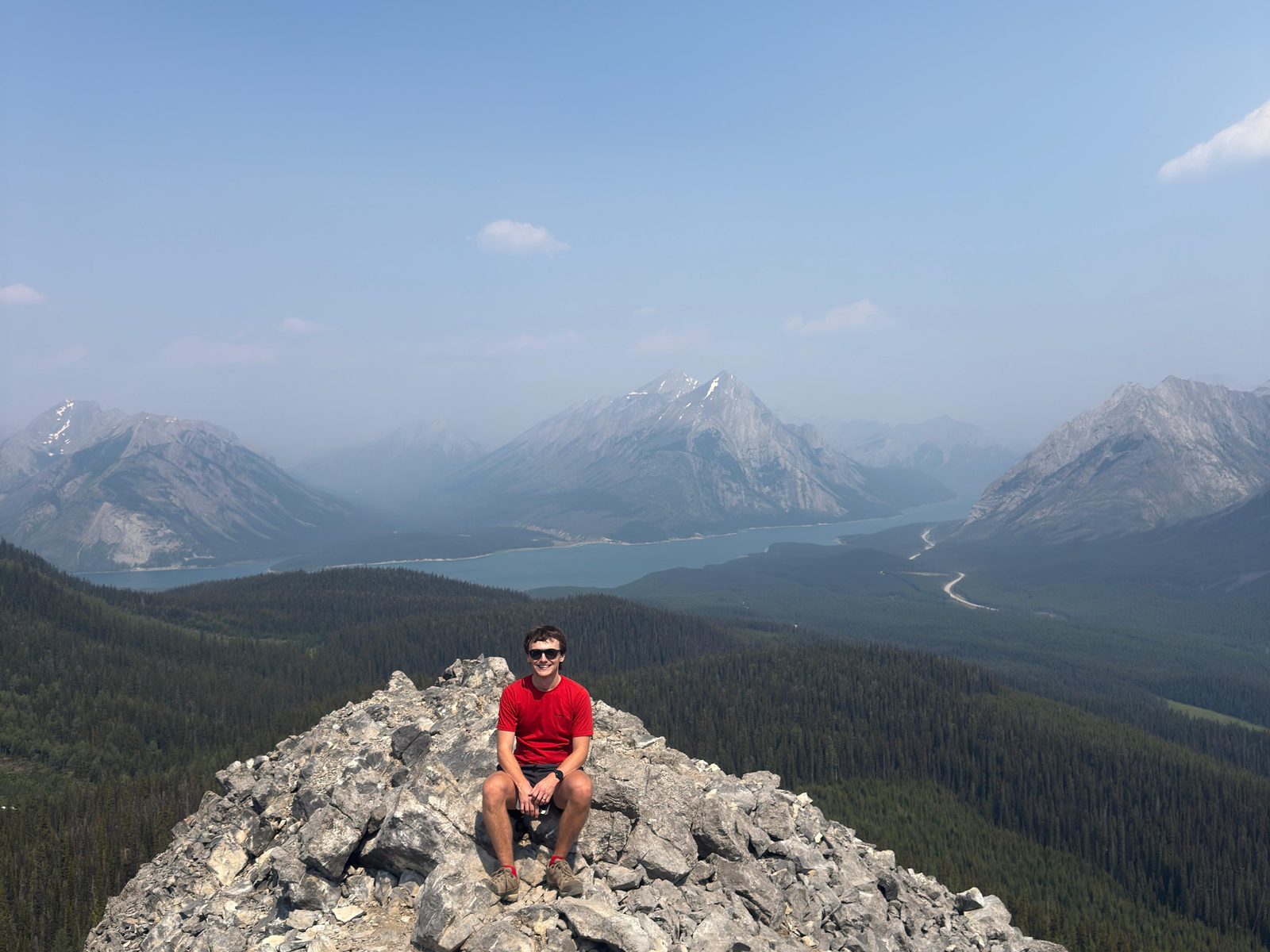 Joe on a mountain summit above a lake in the Canadian Rockies